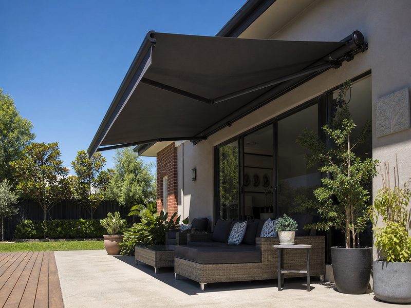Folding arm awning extended over a paved back patio