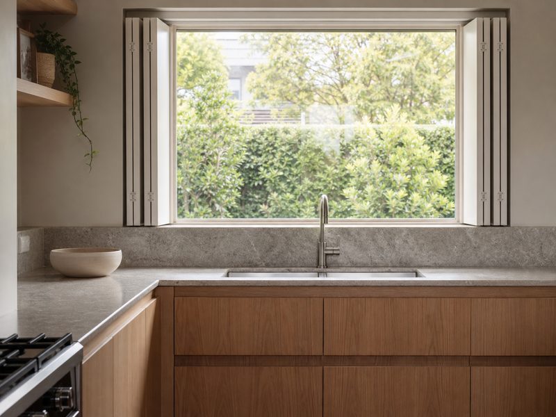 Kitchen window with white plantation shutters folded back